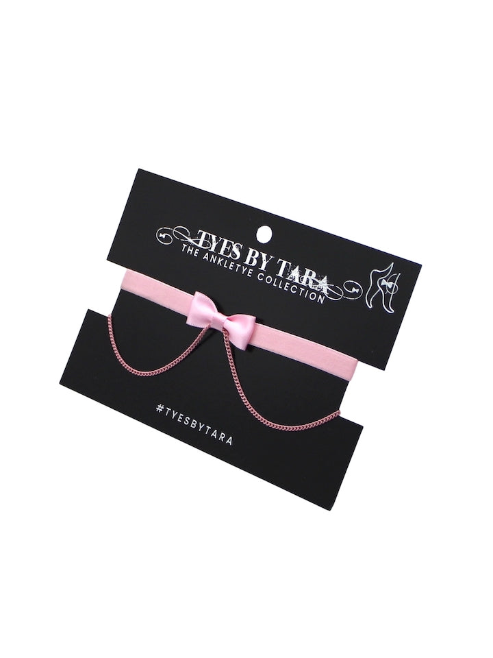 Pink bow anklet with bow on a black card displaying 'Tyes by Tara' brand.
