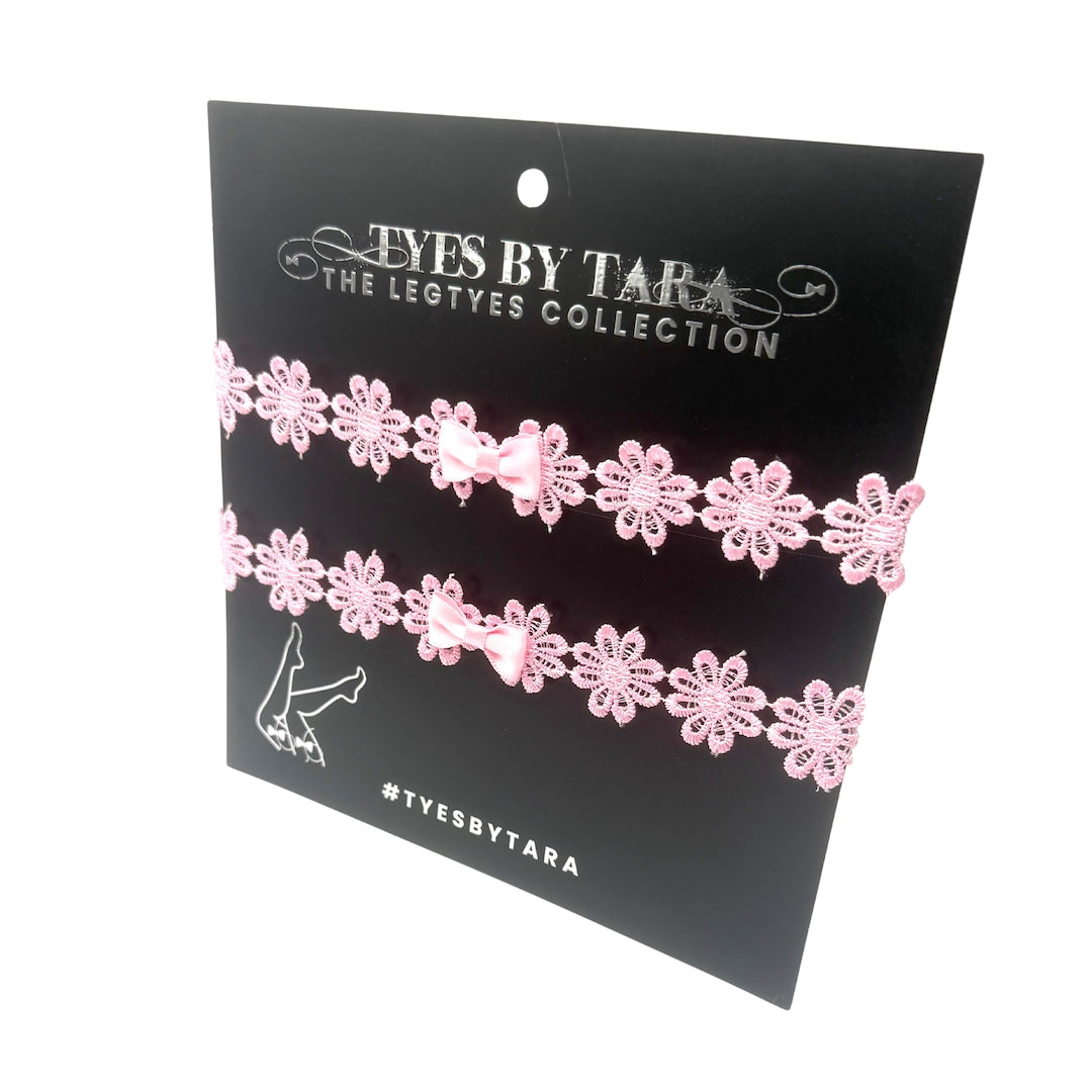 Pink Flower Bow Leg Garters with Adjustable Pink Elastic straps on white background on a black packaging card