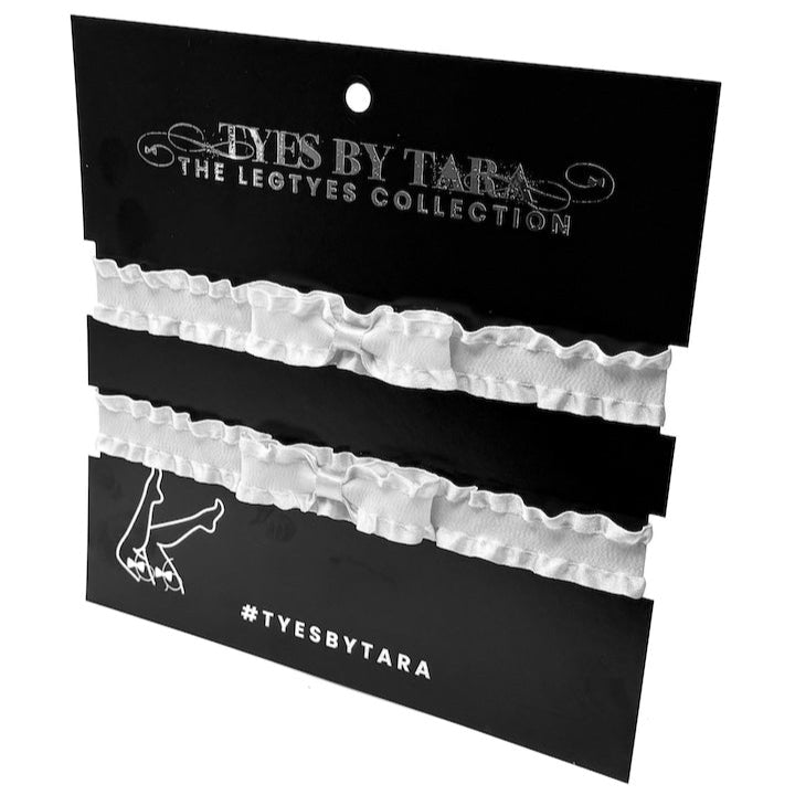 White ruffled leg garters on a black card with 'Tyes by Tara' branding