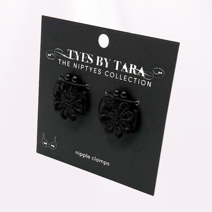 Black flower nipple clamps jewelry on a 'Tyes by Tara' branded card against a white background