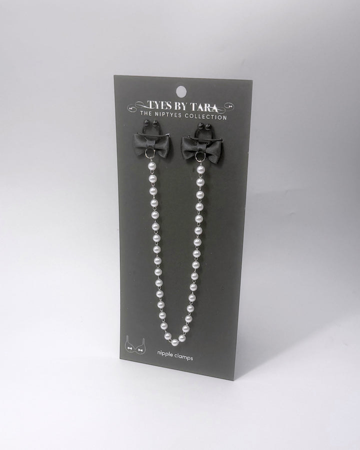 Centerfold Pearl Nipple Clamps with black bows and a creamy pearl strand connecting them on a black retail card