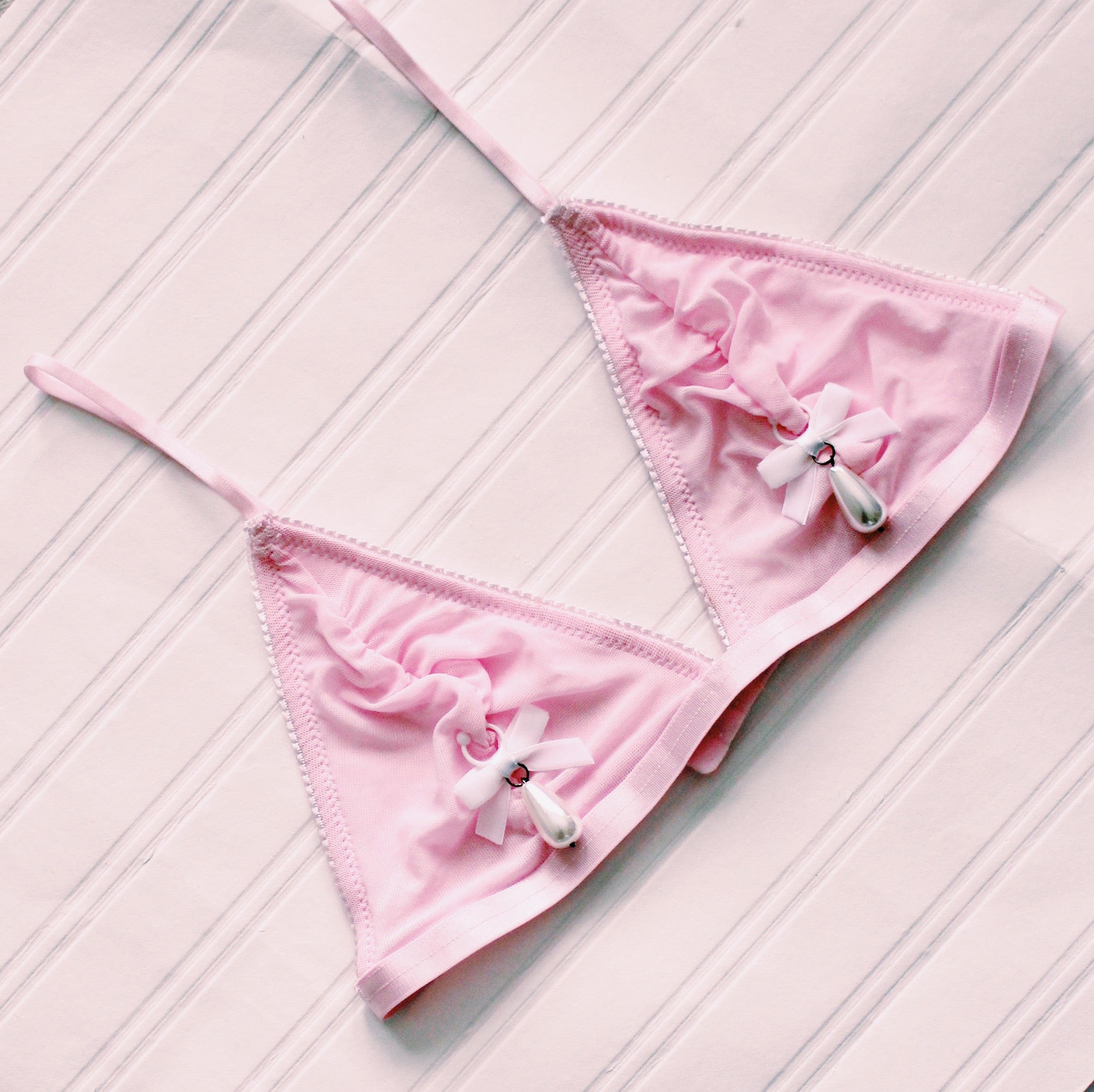 Flatlay of Pink Bra with Marie Antoinette Pearl Nipple Clamps