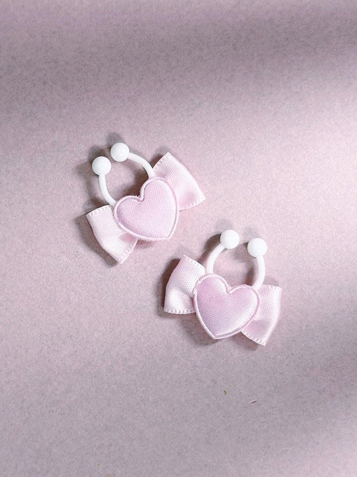 Pair of pink heart-shaped nipple clamps on a light pink background