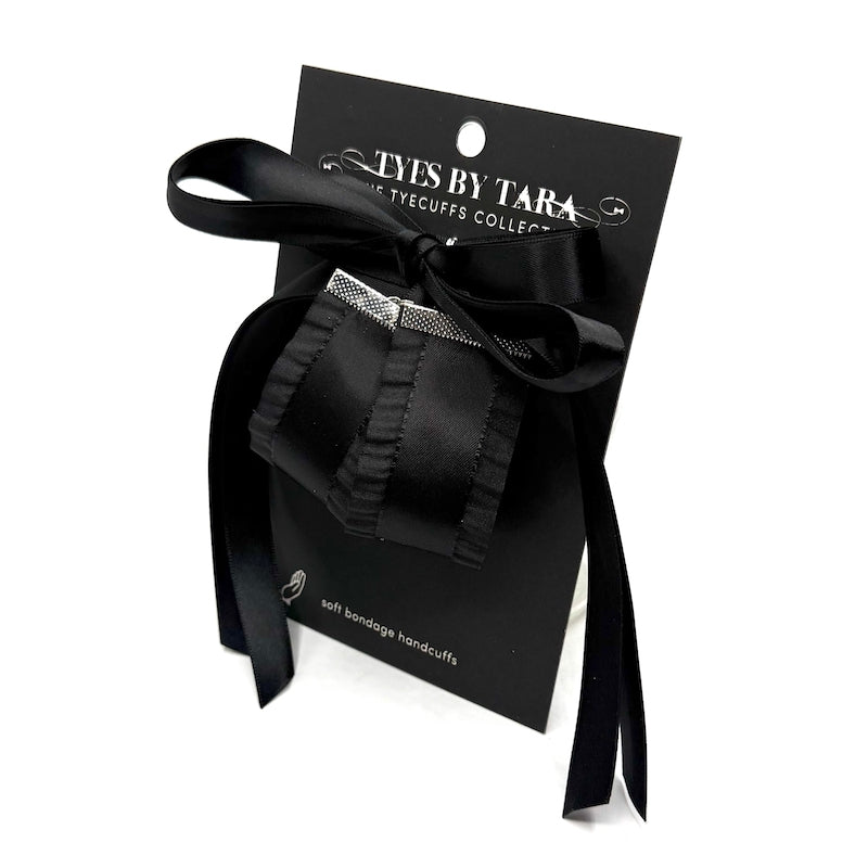 Black bondage handcuffs with satin ribbon packaging on a white background