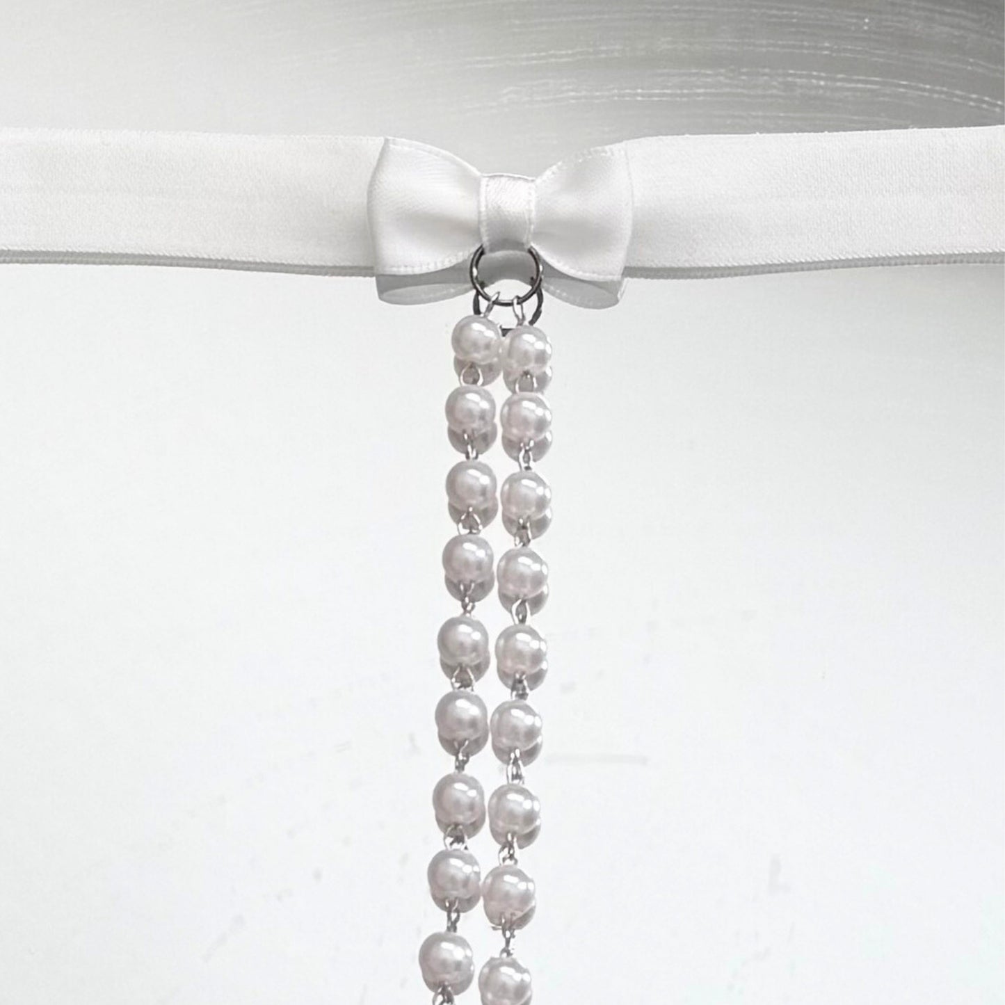 Pearl necklace with a white bow on a white background