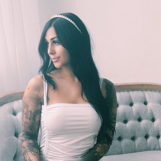 Woman in a white dress with tattoos sitting on a gray couch with Centerfold White Pearl Headband