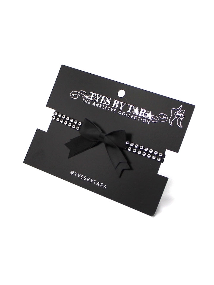 Black sparkly anklets with bow packaging on a white background