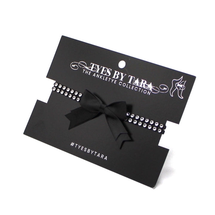 Black sparkly anklets with bow packaging on a white background