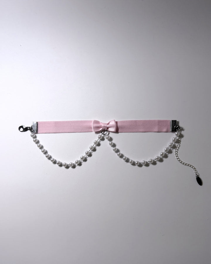 Light Pink Bow Anklet with faux pearl chain drape on light background with pretty shadows