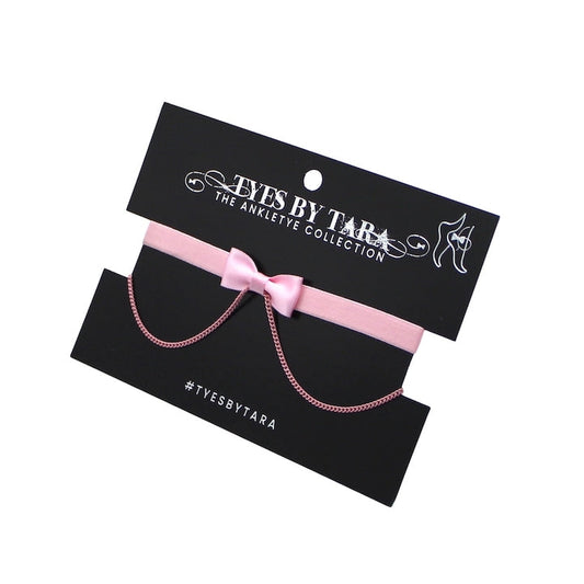 Pink bow anklet with bow on a black card displaying 'Tyes by Tara' brand.