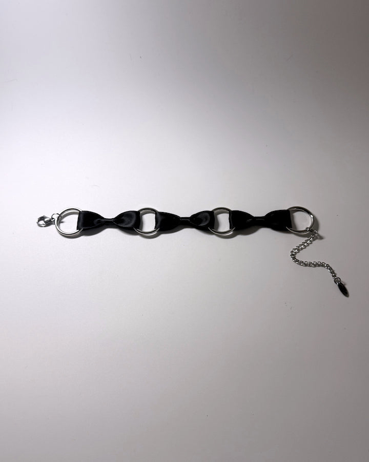 runaway black bow bracelet positioned flat on softly lit surface