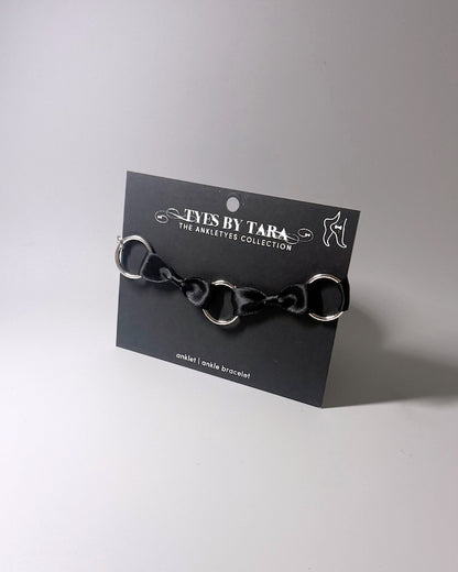 runaway black bow bracelet displayed on a black retail card on softly lit surface