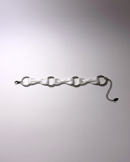 A white satin anklet with silver-tone metal O-rings, a lobster clasp on one end, and a short silver chain extender on the other, displayed on a light gray background.