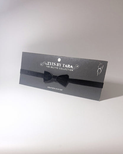 A Black Velvet Bow Belt displayed on a black card