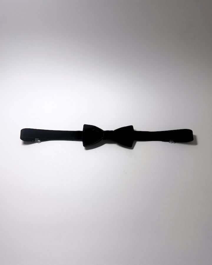 A black velvet bow belt with a matching black elastic strap, laid horizontally on a plain light gray background.
