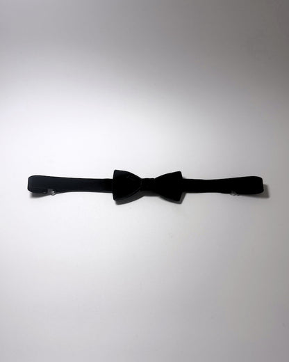 A black velvet bow belt with a matching black elastic strap, laid horizontally on a plain light gray background.
