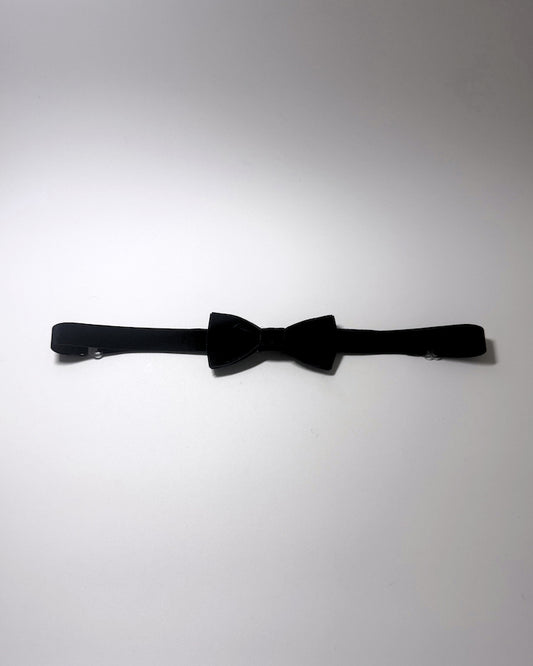 A black velvet bow belt with a matching black elastic strap, laid horizontally on a plain light gray background.