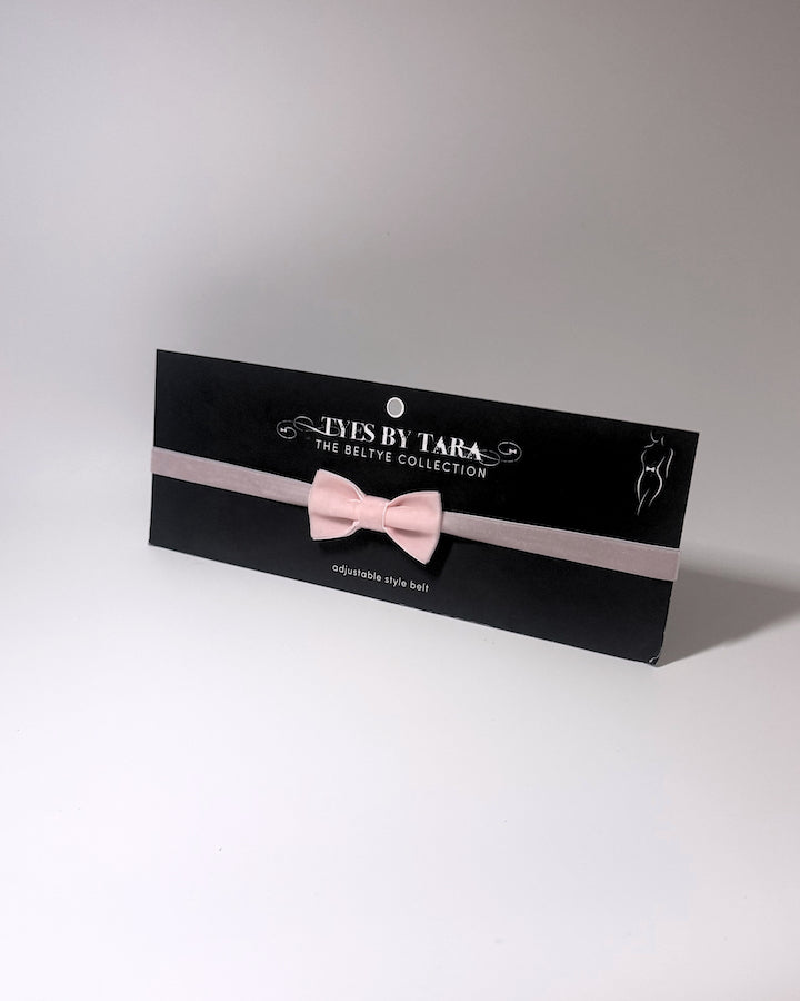 Pink Velvet Bow Belt on black card on a softly lit surface