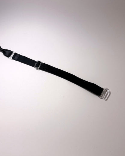 A black adjustable strap with silver metal hardware, including a buckle and a spring ring, laid diagonally on a plain light background.