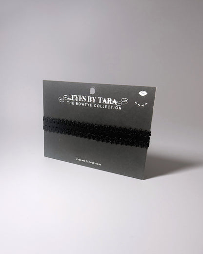 Black Elastic bow choker on light gray background displayed on black retail card