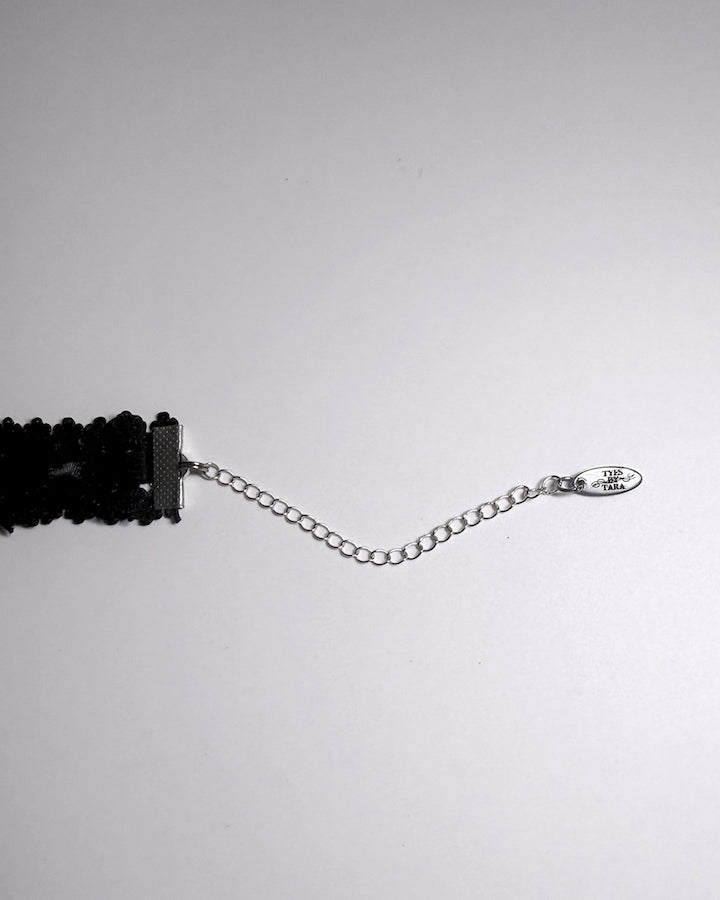 Black Elastic bow choker on light gray background showing logo tag