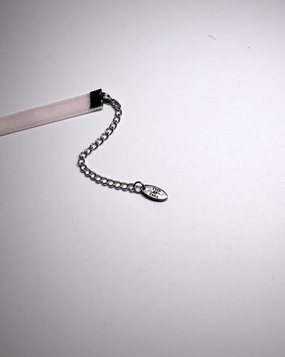 A close-up of a silver chain extender with an oval engraved TYES BY TARA tag on a plain light gray background.