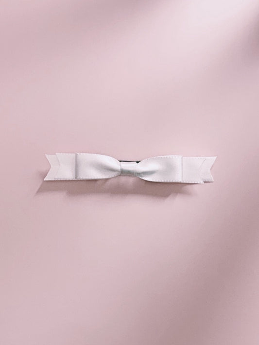 White satin hair bow french barrette on a pink background