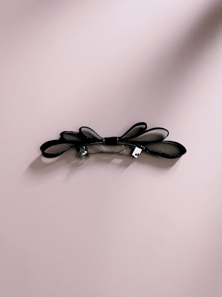 Queen Black Adult Hair Bow with Silver Metallic Trim Viewed from the Side on Pink Background