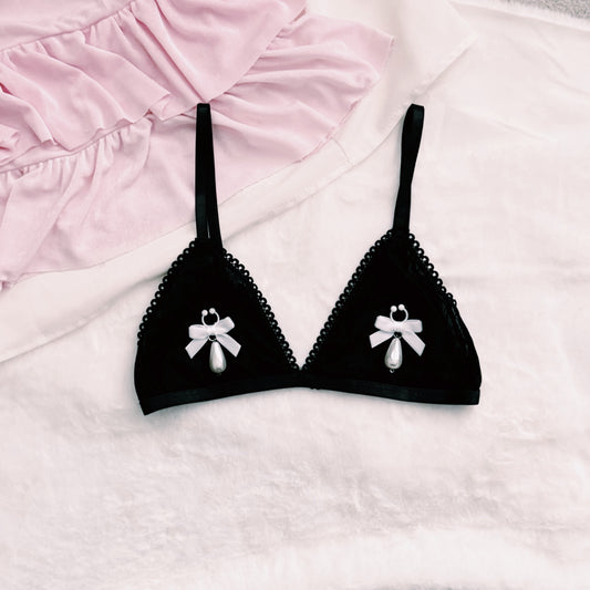 Black bra with white bow nipple clamps jewelry on a pink and white background