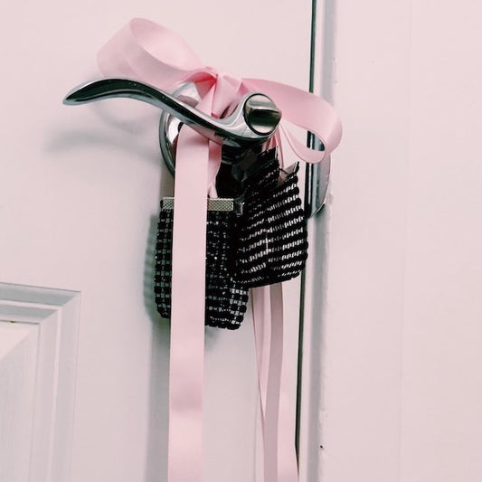 Black Sparkly Handcuffs with Long Pink Satin Ties on Door Knob