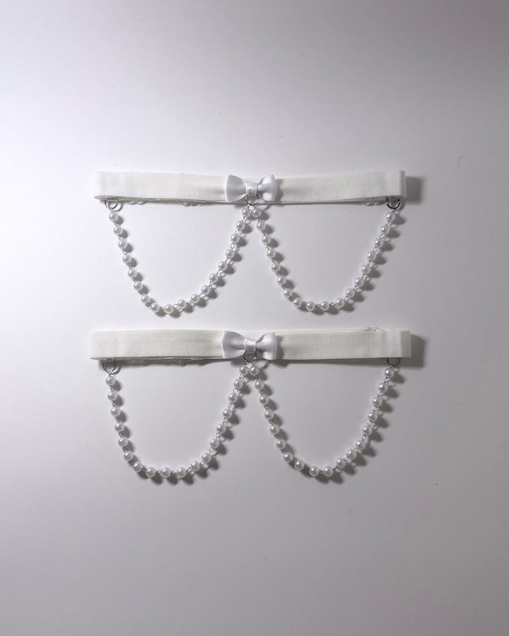White Pearl Leg Garters Two white elastic  garters with pearl bead chains and small white bows, displayed against a plain light gray background. 