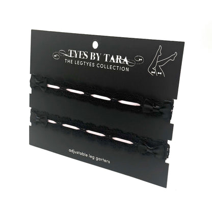 Black adjustable black lace leg garters on a 'Tyes by Tara' branded card.