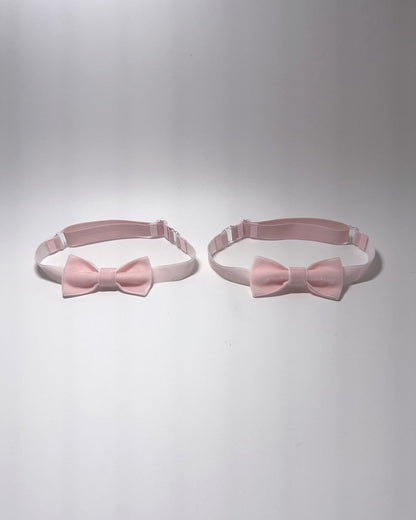 Two light pink bow velvet leg garters with adjustable elastic straps, displayed side-by-side on a light gray background.