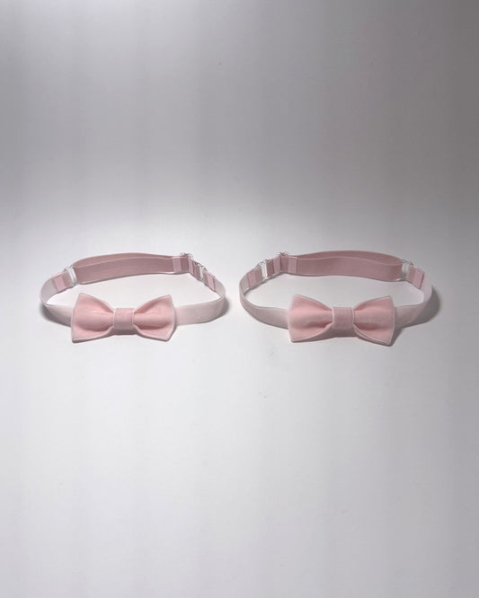 Two light pink bow velvet leg garters with adjustable elastic straps, displayed side-by-side on a light gray background.