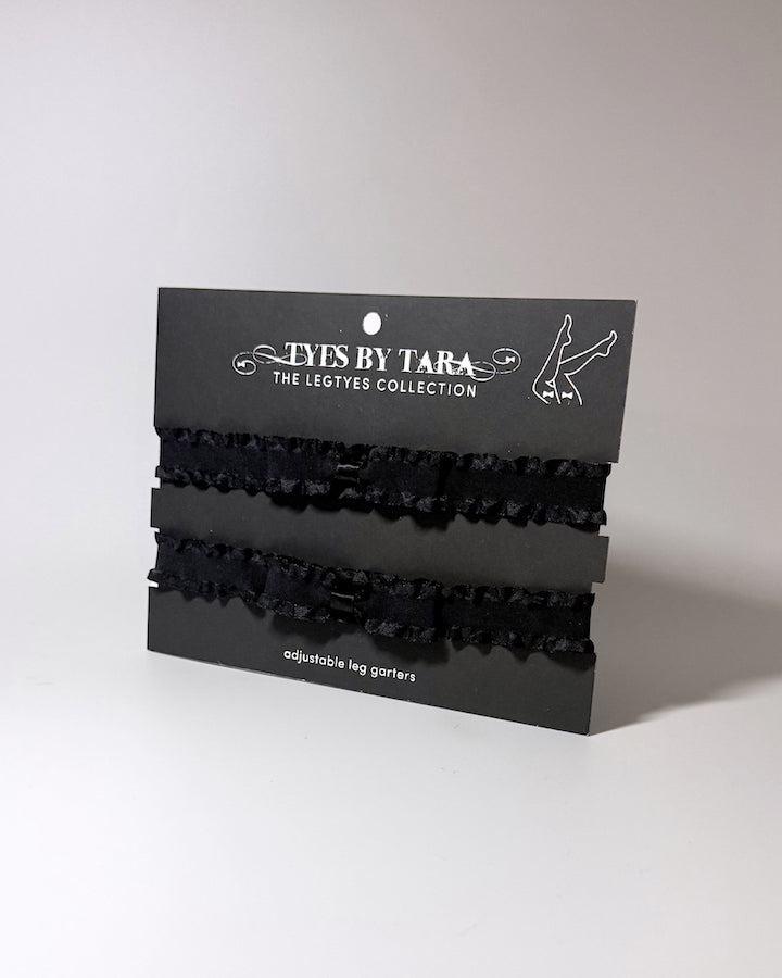 Three black ruffled leg garters displayed on a black retail card labeled 'TYES BY TARA THE LEGTYES COLLECTION' against a plain light gray background.