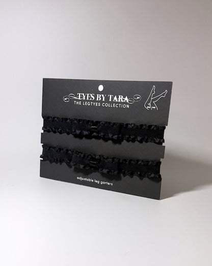 Three black ruffled leg garters displayed on a black retail card labeled 'TYES BY TARA THE LEGTYES COLLECTION' against a plain light gray background.