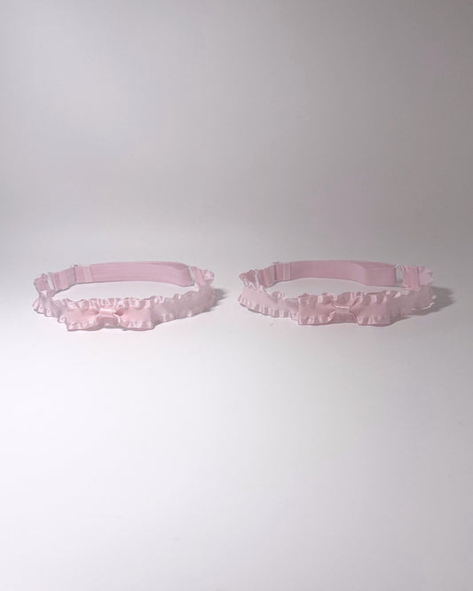 pink ruffled bow leg garters on light gray background