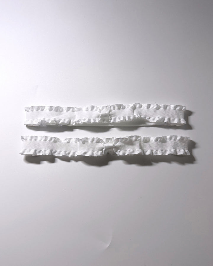White Ruffled Bow Leg Garters displayed on light gray background with soft shadows