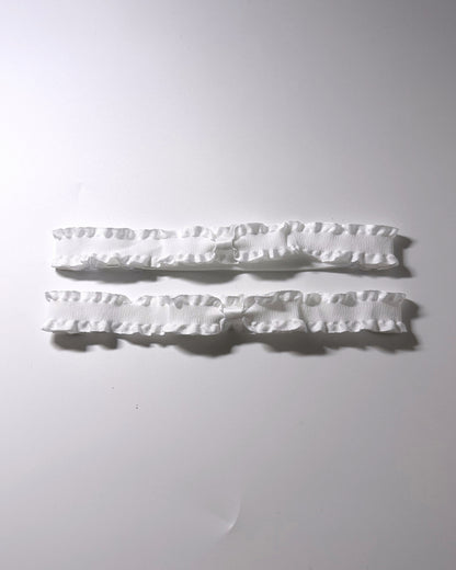 White Ruffled Bow Leg Garters displayed on light gray background with soft shadows