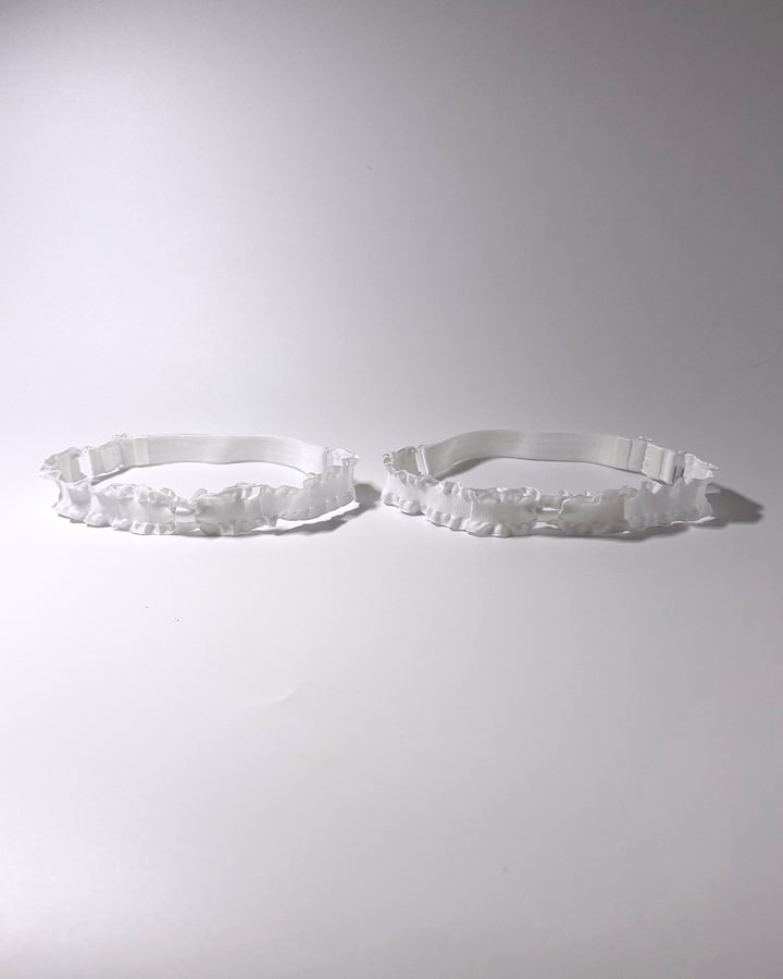 White Ruffled Bow Leg Garters displayed on light gray background with soft shadows