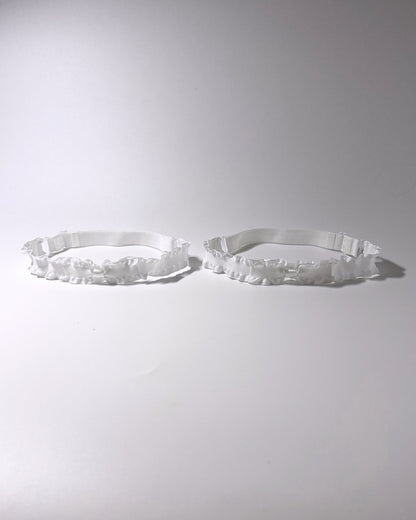 White Ruffled Bow Leg Garters displayed on light gray background with soft shadows