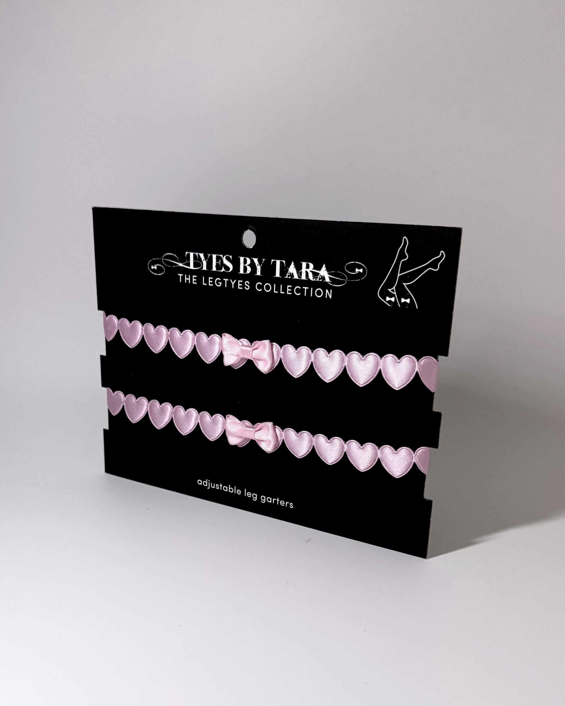 Sweetheart Pink Heart Leg Garters showing adjustable straps displayed on black retail card