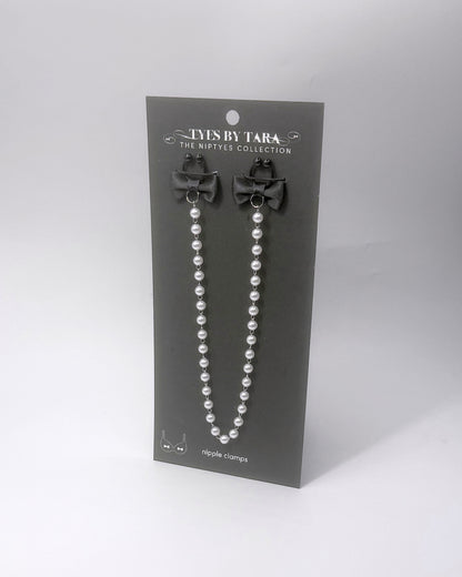Centerfold Pearl Nipple Clamps with black bows and a creamy pearl strand connecting them on a black retail card