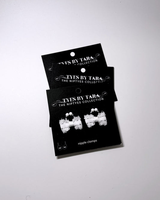 Lady White bow nipple jewelry clamps on black cards