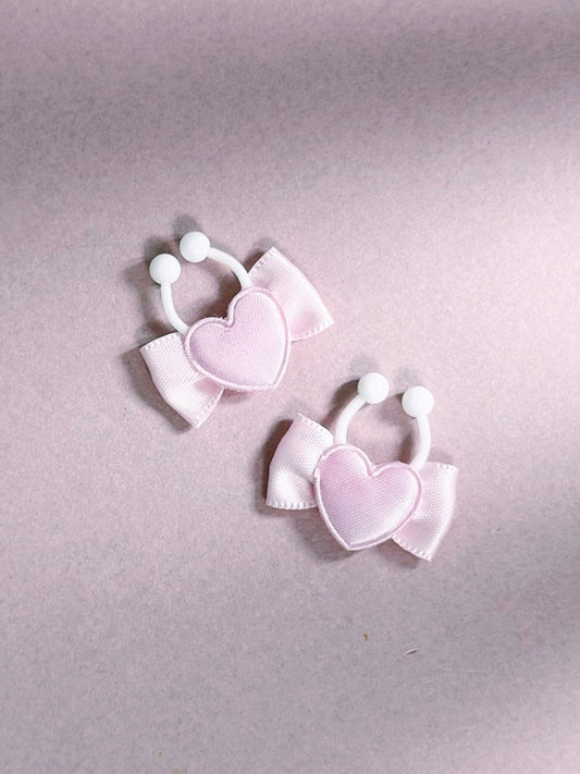 Pair of pink heart-shaped nipple clamps on a light pink background