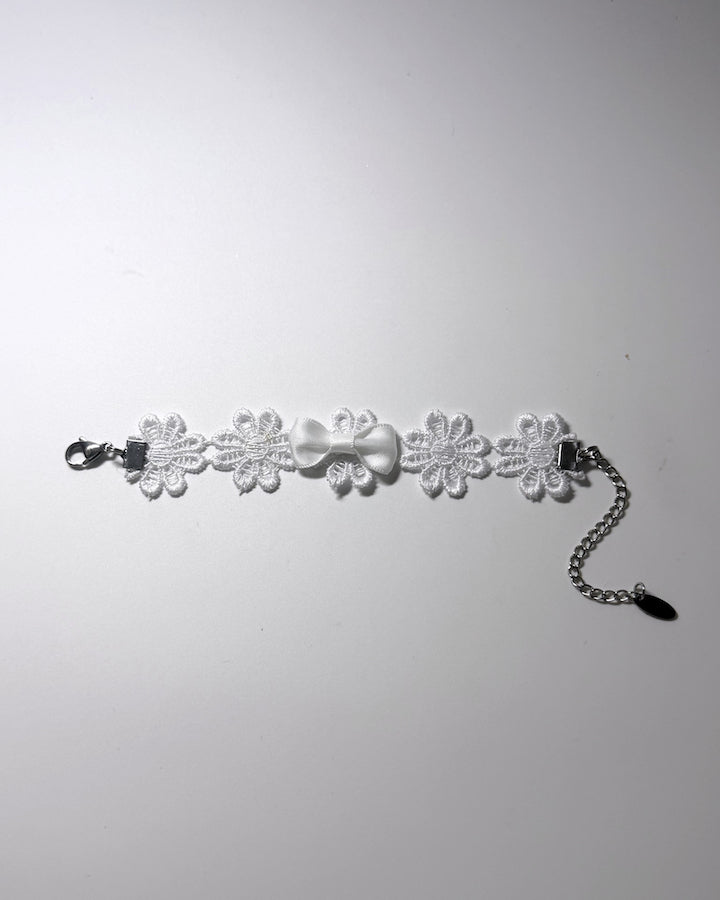 White Flower Bracelet with white bow in the center laid flat against a softly lit background