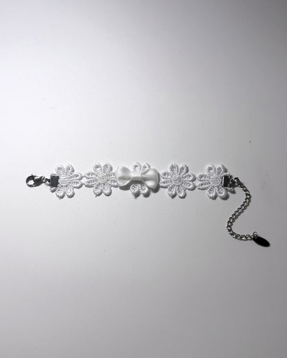 White Flower Bracelet with white bow in the center laid flat against a softly lit background