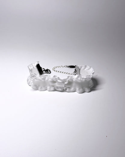 A white ruffled bow bracelet with a silver metal chain extender and lobster clasp, displayed on a clean white background.