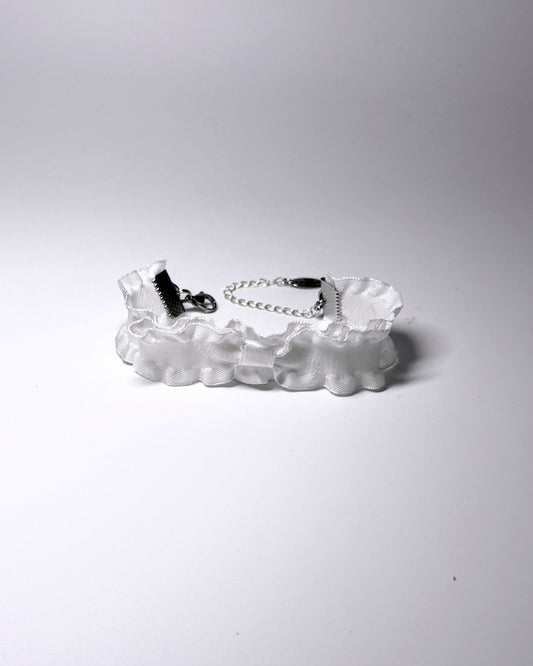 A white ruffled bow bracelet with a silver metal chain extender and lobster clasp, displayed on a clean white background.