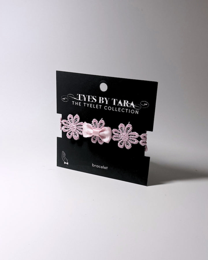 Pink Flower Bow Bracelet displayed on an black retail card on softly lit background